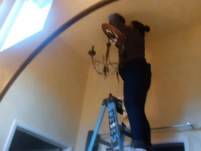Electrician installing a chandelier in a Margaret residence